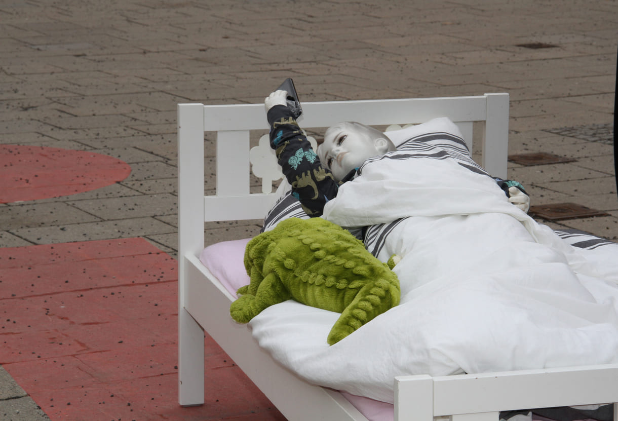 Puppe im Kinderbett starrt aufs Handy - aktionistisch machte der Unicef-Jugendbeirat auf die eigenen Forderungen in Sachen digitaler Kinderschutz aufmerksam