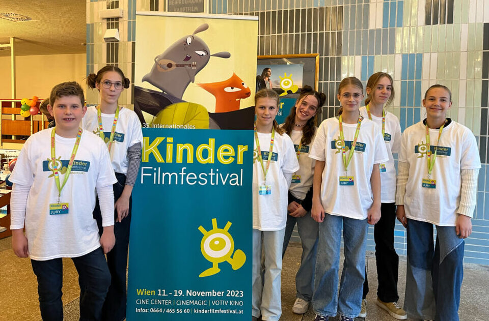 Die Kinderjury: Oliver (11 Jahre), Emma (12), Mathilda (11), Finni (12), Franzi (11), Ruth (13), Mia (11) im Foyer des Gartenbaukinos mit dem Plakat des Kinderfilm-Festivals