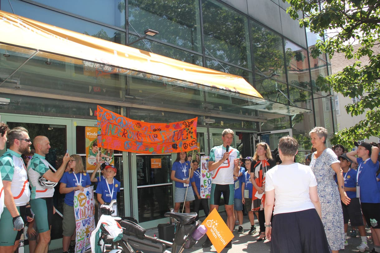 Großes Hallo mit Transparent, Plakaten, Jubel und Reden zum Abschluss der Friedens-Radfahrt am Campus der Uni Wien