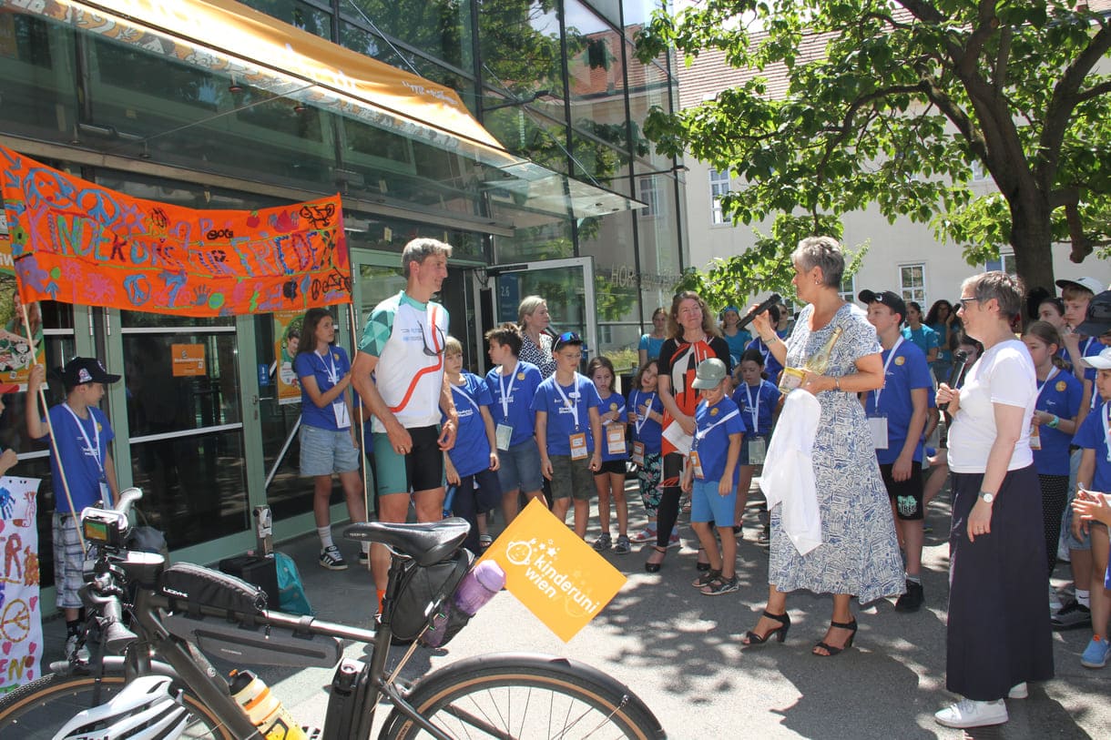 Großes Hallo mit Transparent, Plakaten, Jubel und Reden zum Abschluss der Friedens-Radfahrt am Campus der Uni Wien
