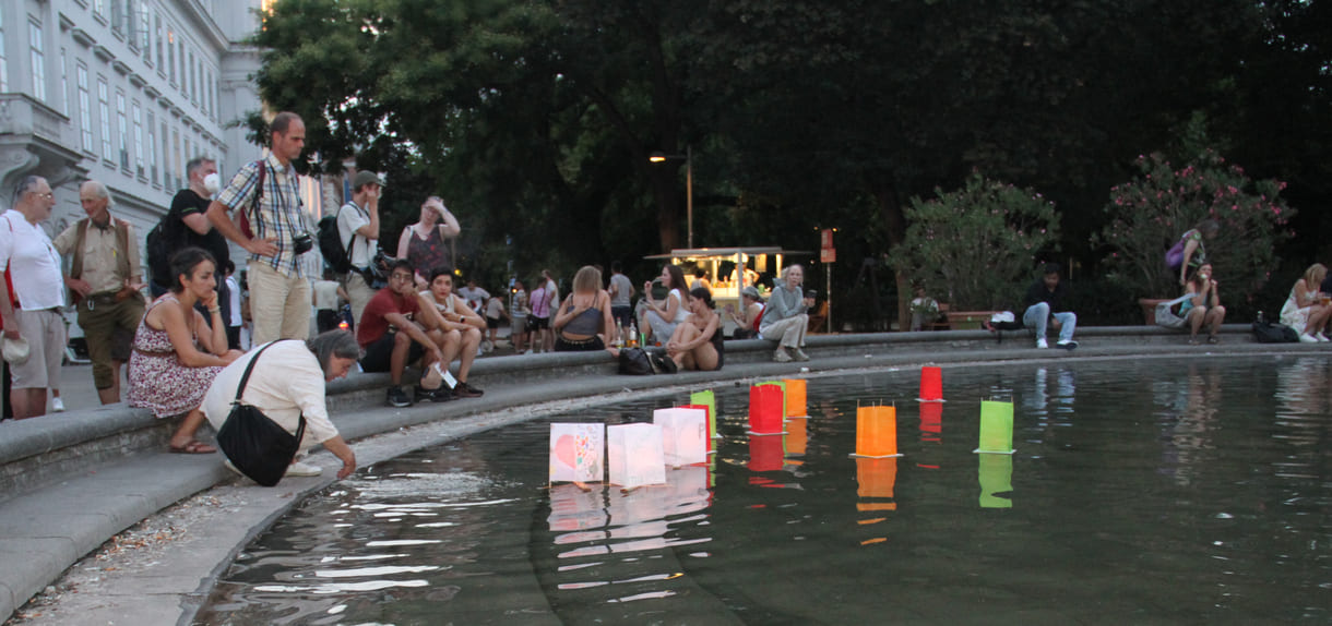 Laternen werden aufs Wasser des Teiches am Karlsplatz gesetzt