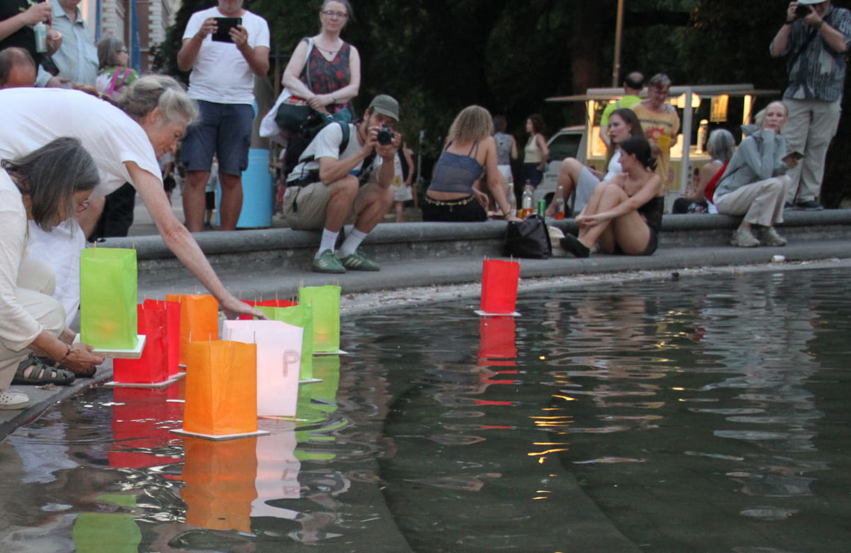 Laternen werden aufs Wasser des Teiches am Karlsplatz gesetzt