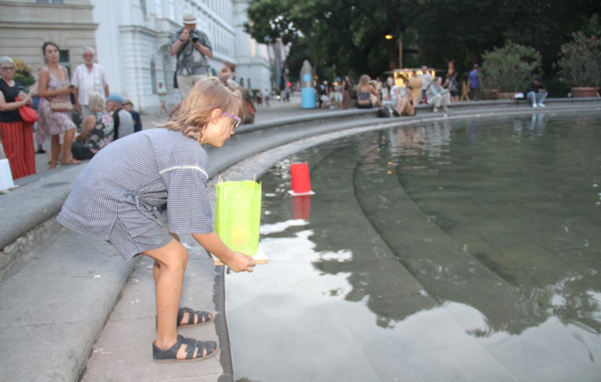 Laternen werden aufs Wasser des Teiches am Karlsplatz gesetzt