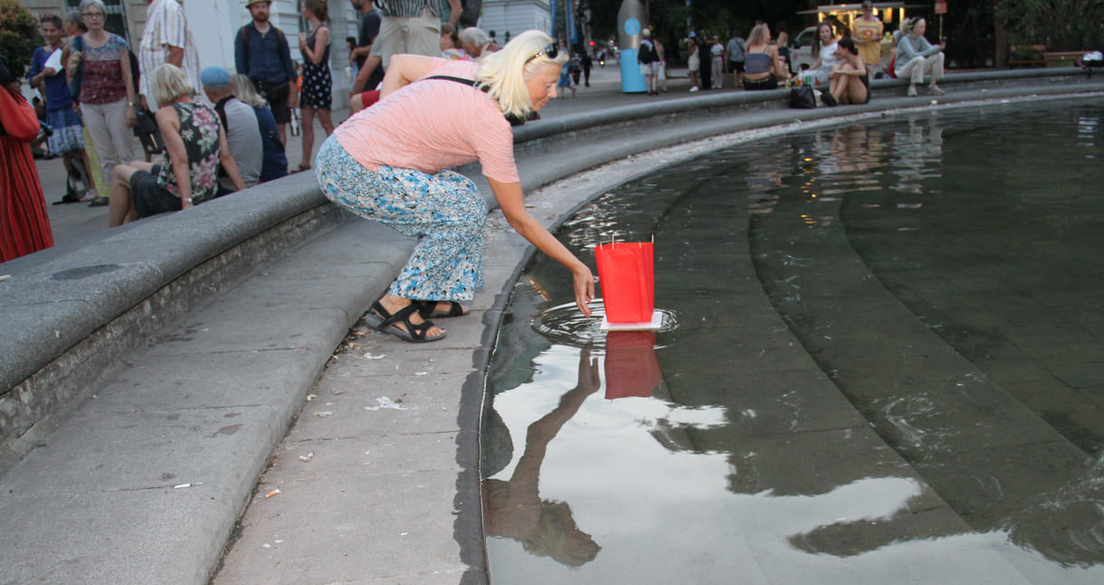 Laternen werden aufs Wasser des Teiches am Karlsplatz gesetzt