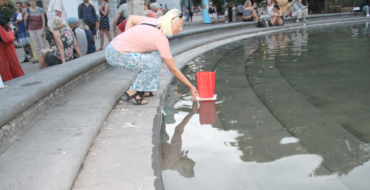 Laternen werden aufs Wasser des Teiches am Karlsplatz gesetzt
