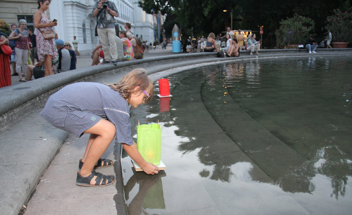 Laternen werden aufs Wasser des Teiches am Karlsplatz gesetzt