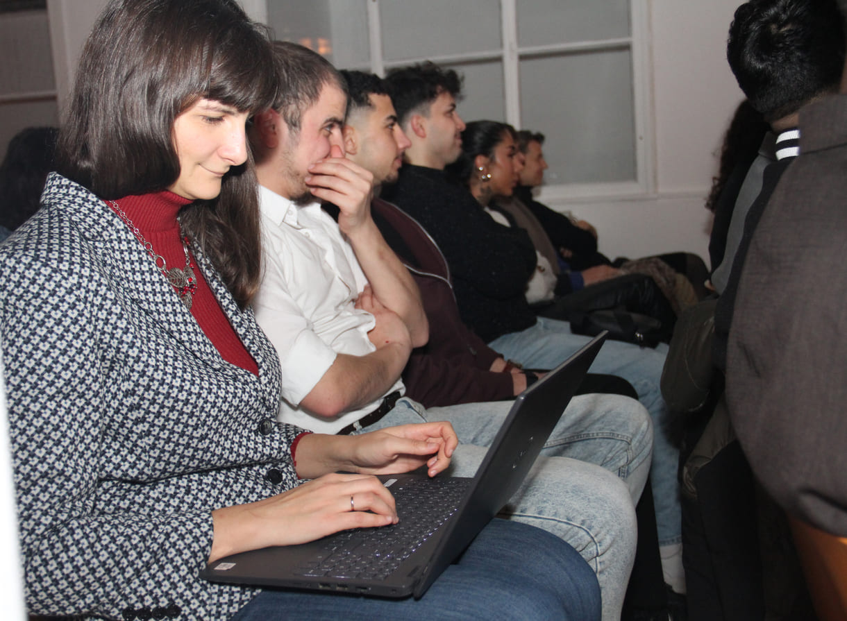 Lehrerin am Laptop und ihre Schüler:innen des Jugendcolleges, das den Gruppenpreis gewonnen hat