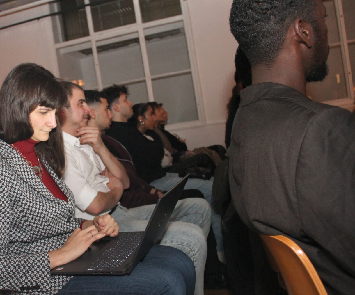 Lehrerin am Laptop und ihre Schüler:innen des Jugendcolleges, das den Gruppenpreis gewonnen hat