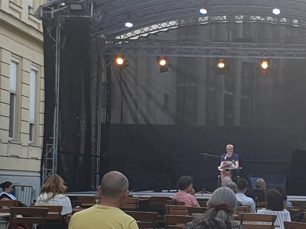 Lesung von Maria Muhar - klein-winzig auf der weit entfernten Bühne, davor Publikum von hinten