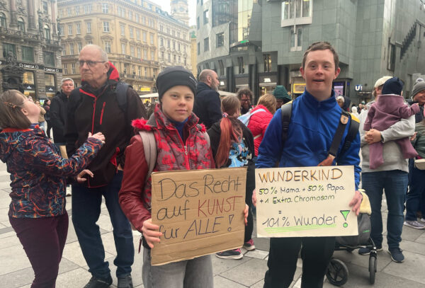 Aktivist:innen mit Kartontafeln mit Hand geschriebenen Sprüchen