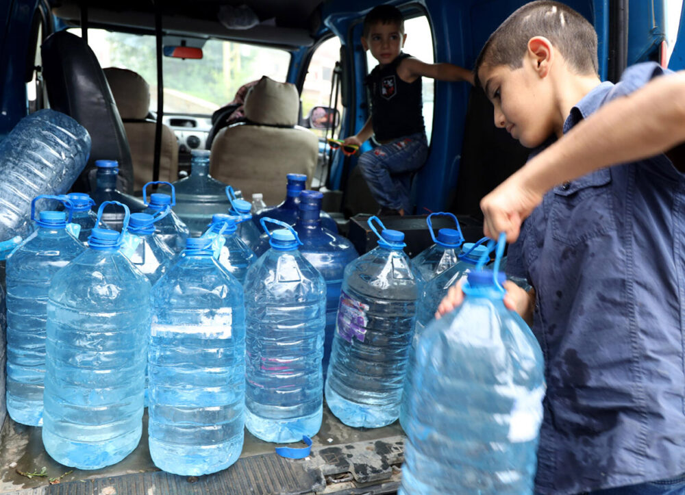 Eine Familie transportiert große Wasserflaschen aus einer Quelle nach Hause