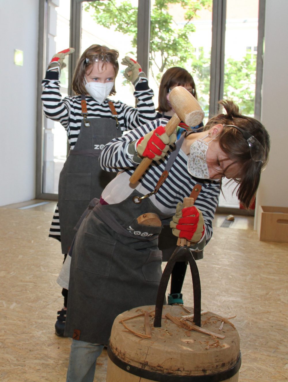 Kind schlägt Holzstück durch Locheisen