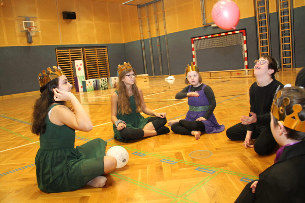 Tänzer:innen, die nciht gerade dran sind, suchen sich stille Beschäftigungen - hier mit Luftballon-Kreisspiel