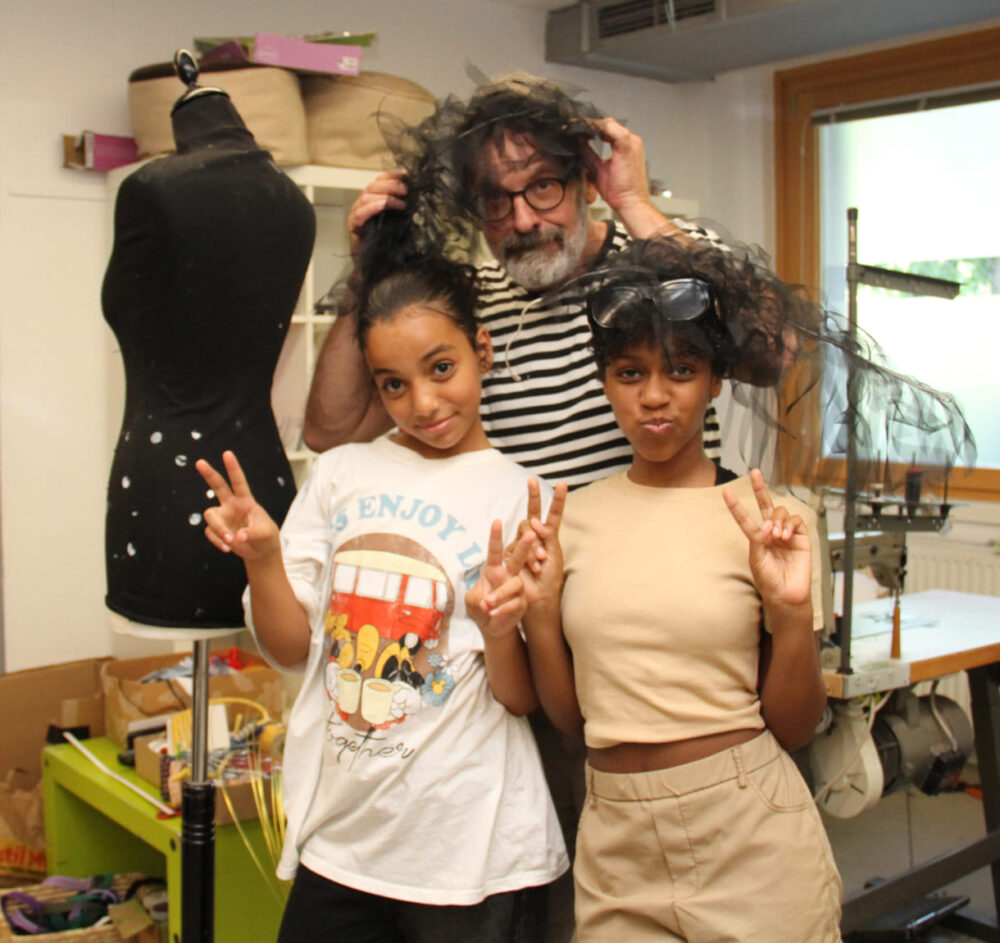 Die beiden Designerinnen mit dem Kids-in-Fashion-Erfinder und den schwarzen Federn