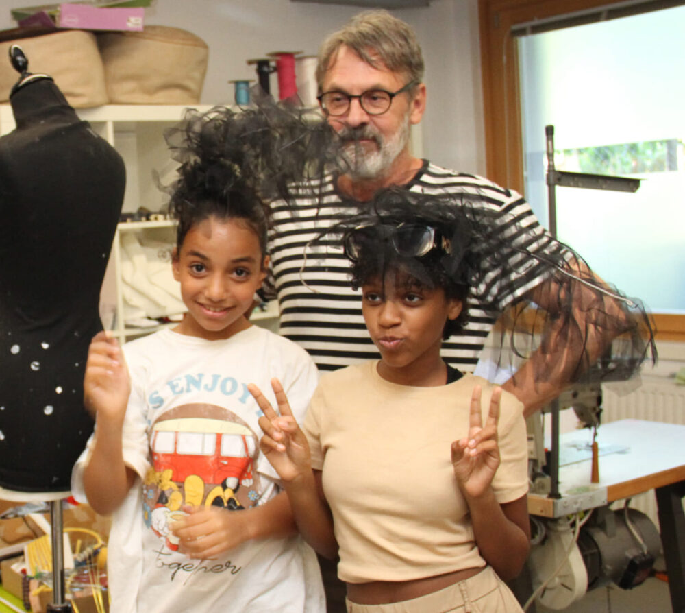 Die beiden Designerinnen mit dem Kids-in-Fashion-Erfinder und den schwarzen Federn