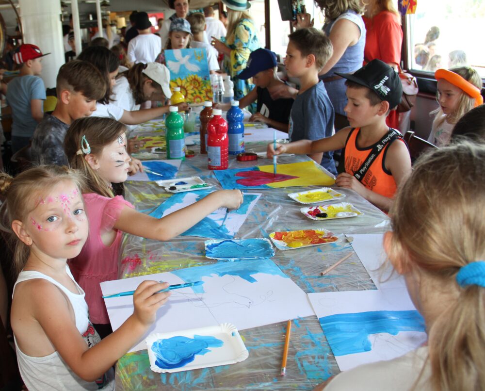 Viele Kinder malen Friedenstauben mit ukrainisch blau-gelben Hintergrund