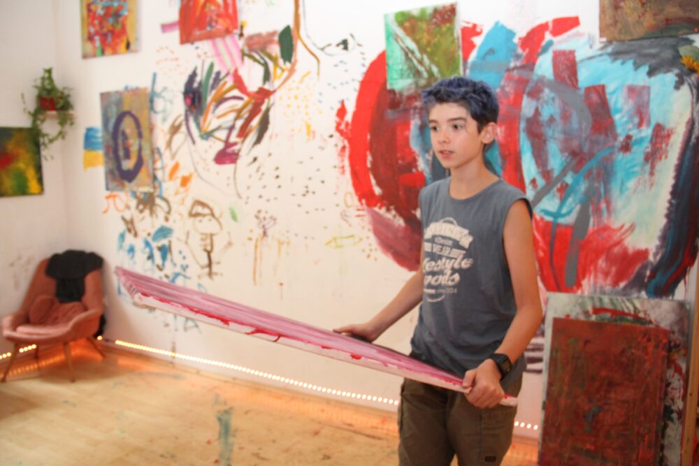 Der junge Maler mit einigen seiner Bilder