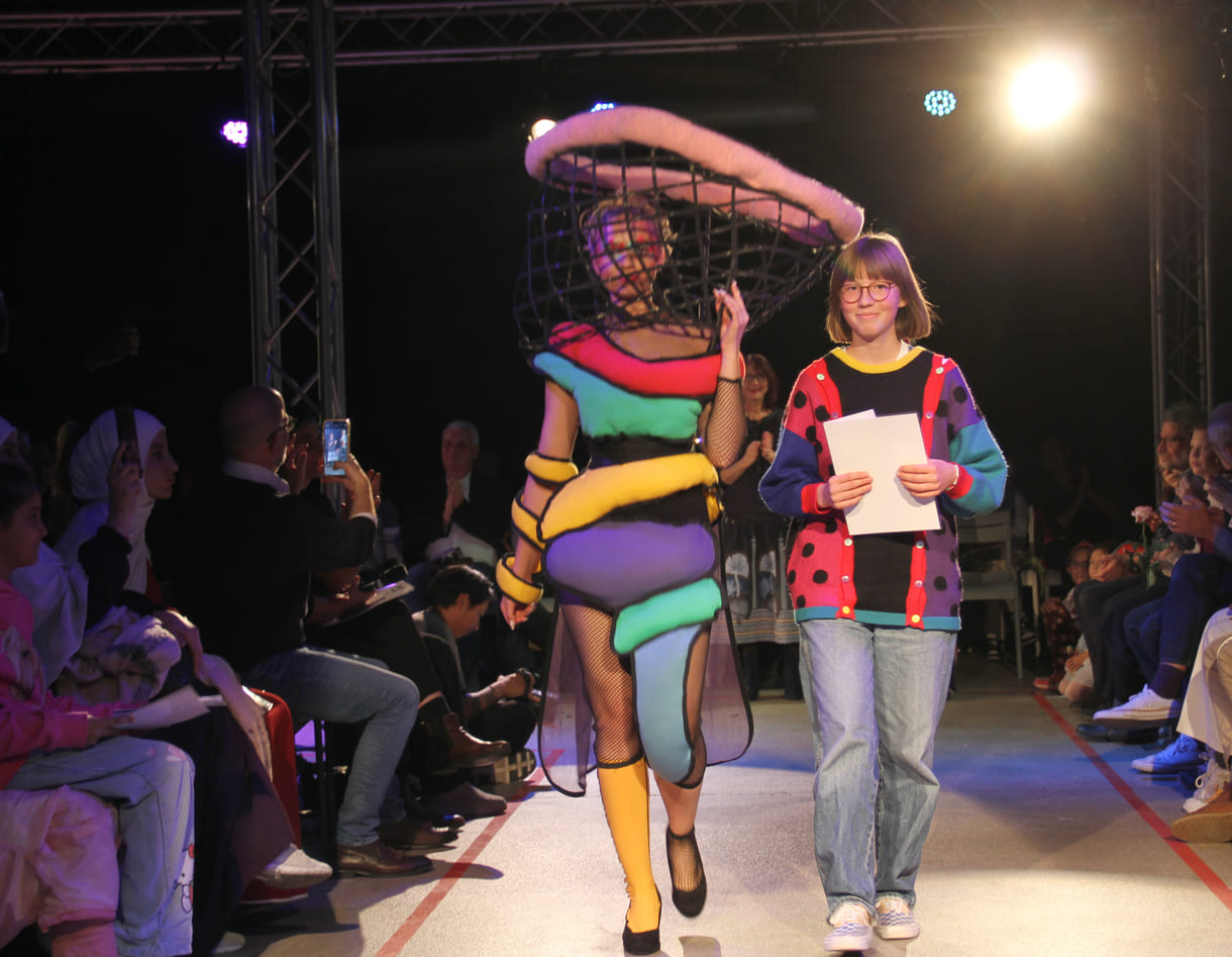 Selber im bunten, kreativen Pullover, entwarf die Siegerin in der mittleren Altersgruppe, Holly Arndold, ein farbenfrohes Kleid mit extravagantem Kopfteil