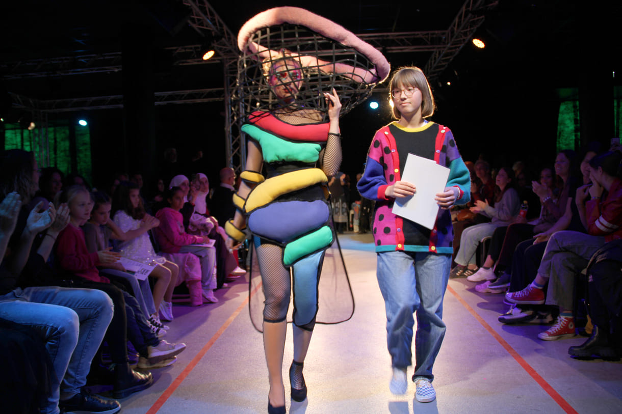 Selber im bunten, kreativen Pullover, entwarf die Siegerin in der mittleren Altersgruppe, Holly Arndold, ein farbenfrohes Kleid mit extravagantem Kopfteil