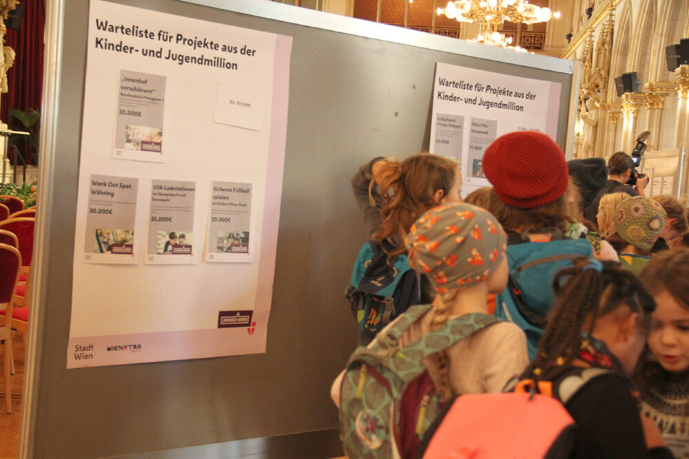 Junge und jüngste Abgeordnete studieren die Plakate der Ausschüsse bzw. der projekte auf der Waeteliste über die sie abstimmen konnten