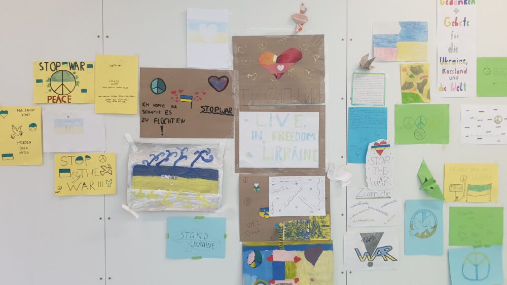 Friedenswünsche und Gedanken - geschieben, gezeichnet und gebastelt - an Wänden der Schul-Aula