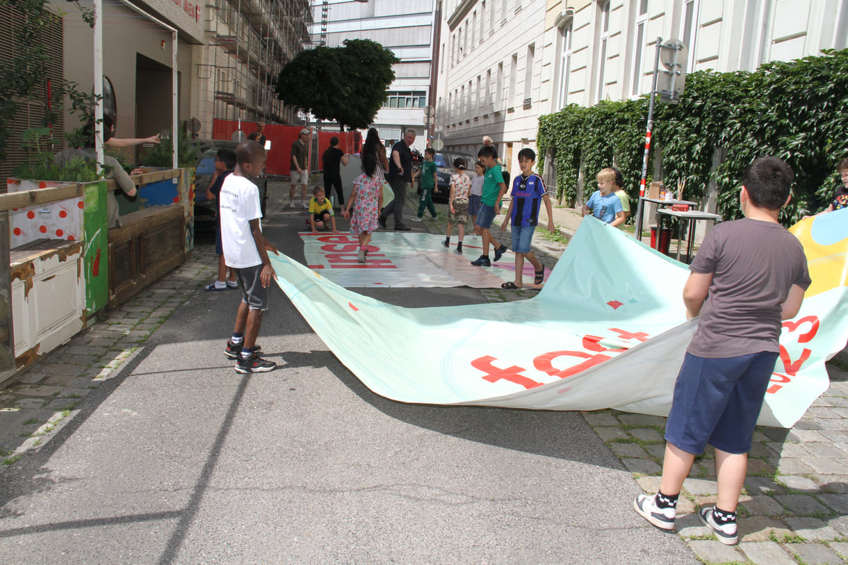 Kinder bringen Planen früherer Banner aus der Schule - die Rückseite wird Mal- und Erde-Pflanz-Unterlage