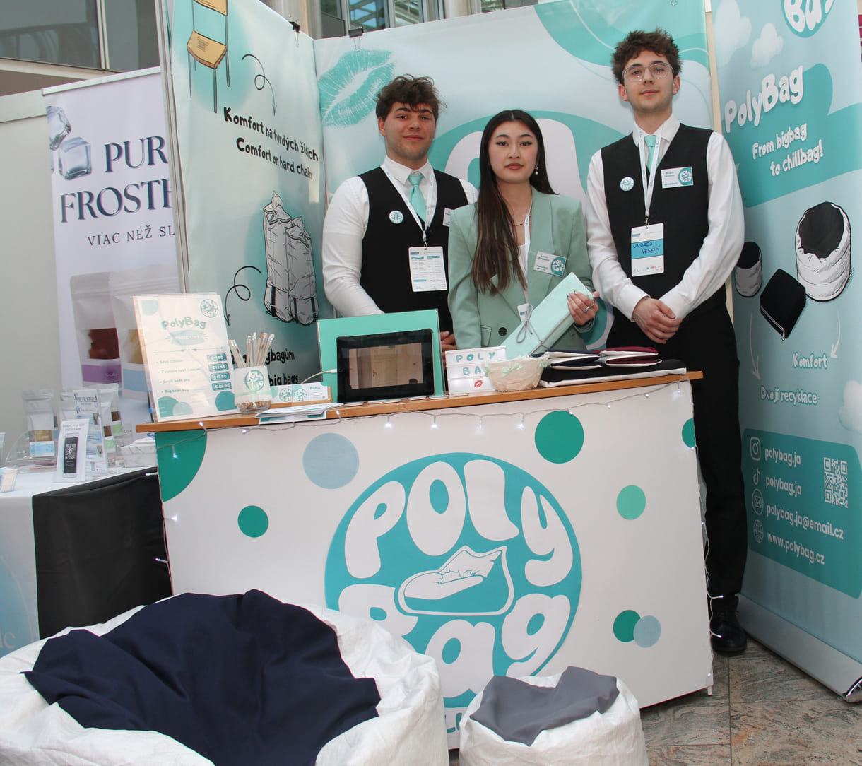 Drei HAK-Schüler:innen aus dem tschechischen Hradec Králové mit - noch nicht gefüllten, aber gefalteten - Sitzsäcken, vor dem Stand zwei mit Polymer-kunststoff gefüllte Lümmelsäcke