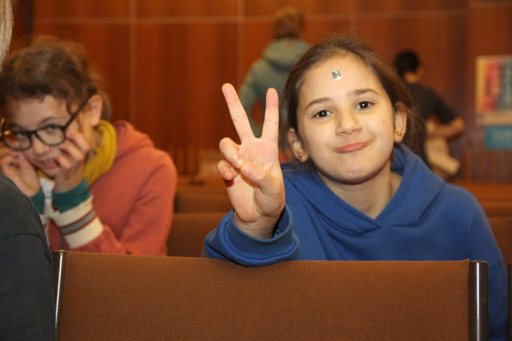 Kinder zeigen ihre verschiedenfarbigen Buchstaben-Sticker - je nach Workshop