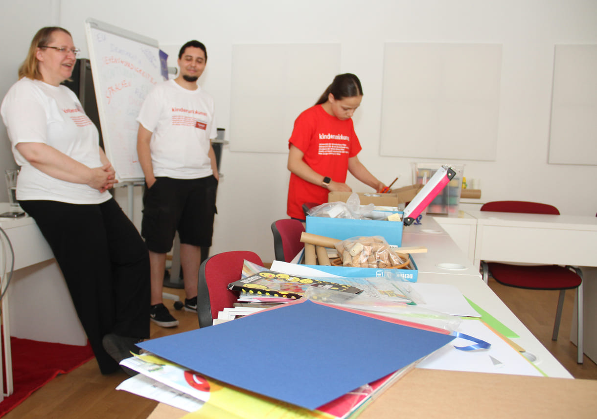 Studierende und Lehrende vor den Tischen mit Materialien