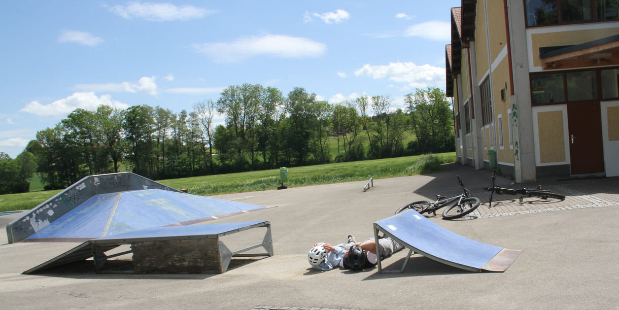 zwei der drei radler legen sich zwischen zwei Ramps, der dritte springt mit dem Rad drüber