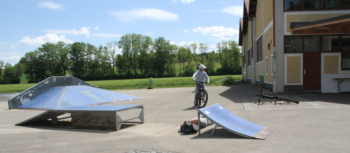 zwei der drei radler legen sich zwischen zwei Ramps, der dritte springt mit dem Rad drüber