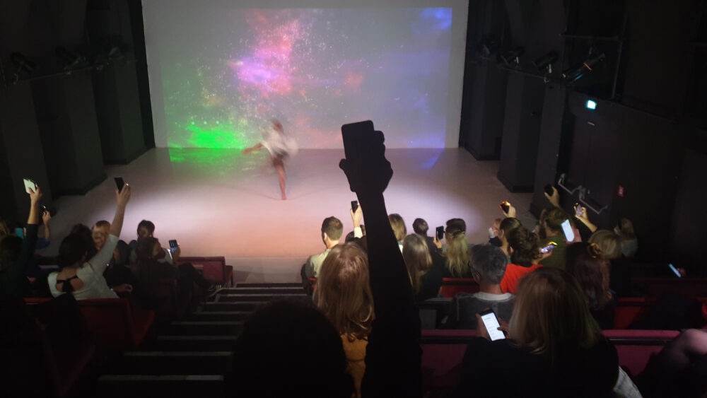 Publikum schickt bunte Handy-Lichter zum Tänzer auf der Bühne