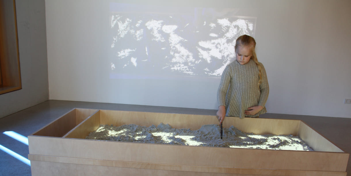 Was Kinder in diesem Sandkasten gestalten, ist als Live-Video an der Wand zu sehen