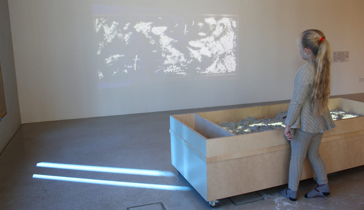 Was Kinder in diesem Sandkasten gestalten, ist als Live-Video an der Wand zu sehen