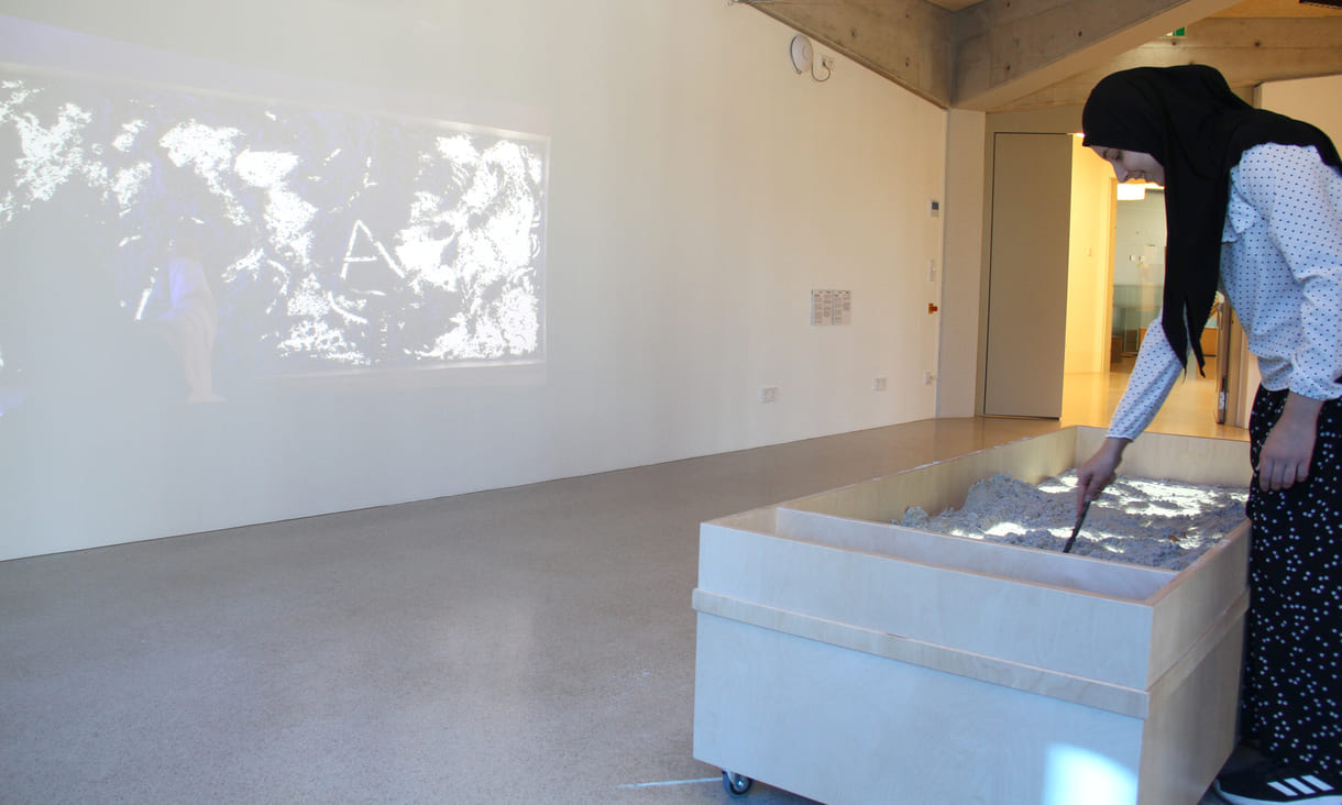 Was Kinder in diesem Sandkasten gestalten, ist als Live-Video an der Wand zu sehen