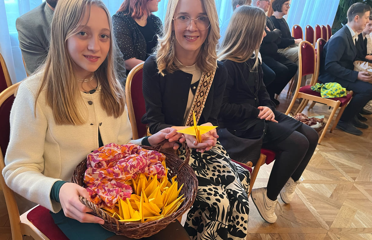 Schülerinnen mit Korb voller Origami-Kraniche