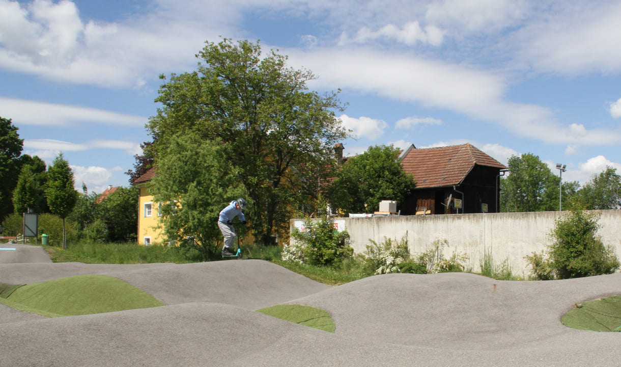 Einer des Radler-Trios düst auch mit einem Scooter über die Pumptrack-Strecke