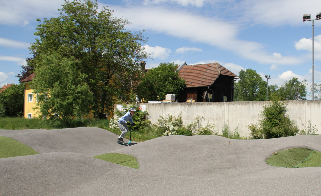 Einer des Radler-Trios düst auch mit einem Scooter über die Pumptrack-Strecke