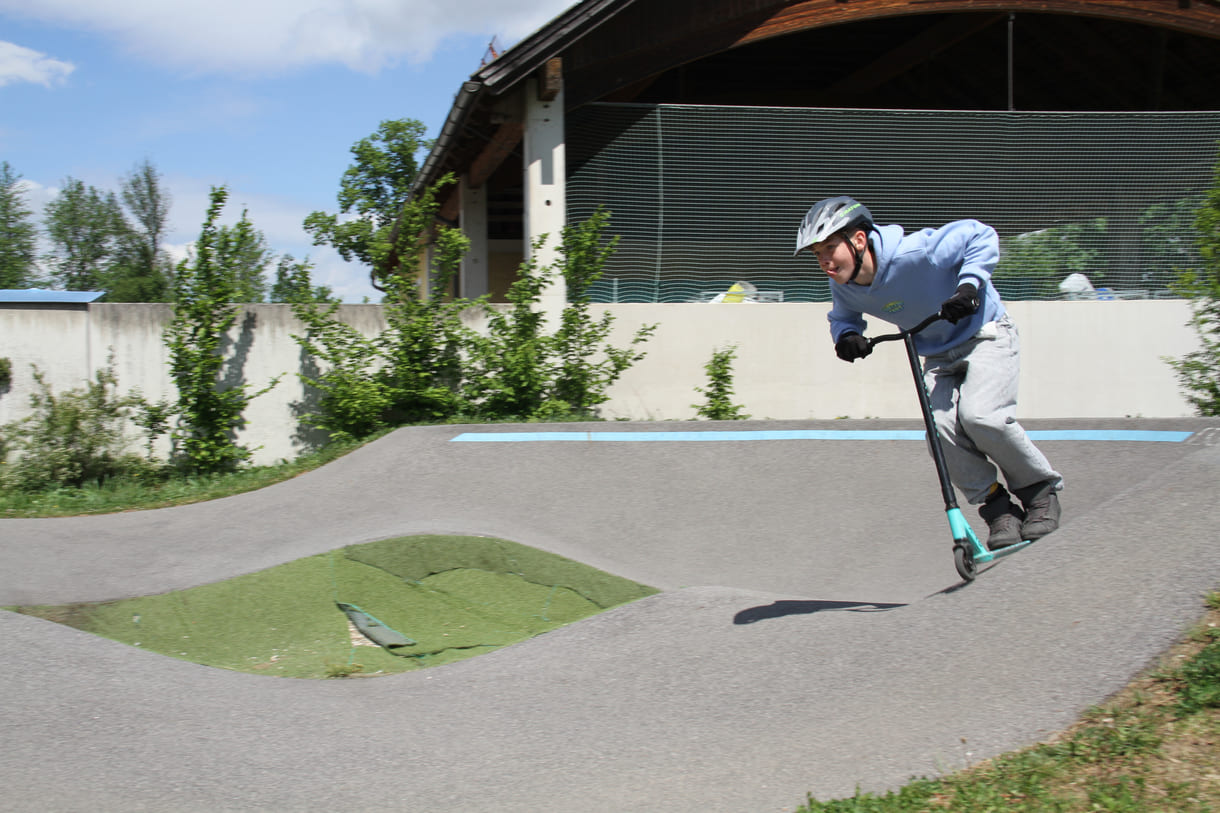 Einer des Radler-Trios düst auch mit einem Scooter über die Pumptrack-Strecke