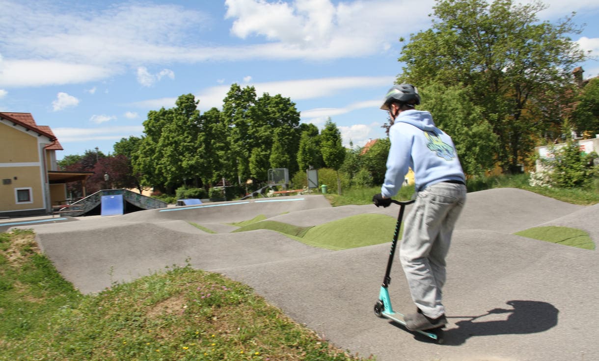 Einer des Radler-Trios düst auch mit einem Scooter über die Pumptrack-Strecke