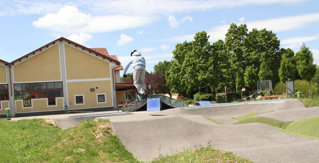 Einer des Radler-Trios düst auch mit einem Scooter über die Pumptrack-Strecke