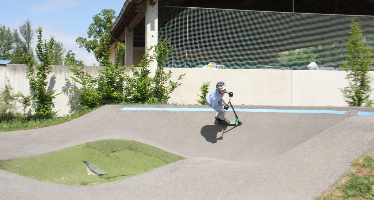 Einer des Radler-Trios düst auch mit einem Scooter über die Pumptrack-Strecke