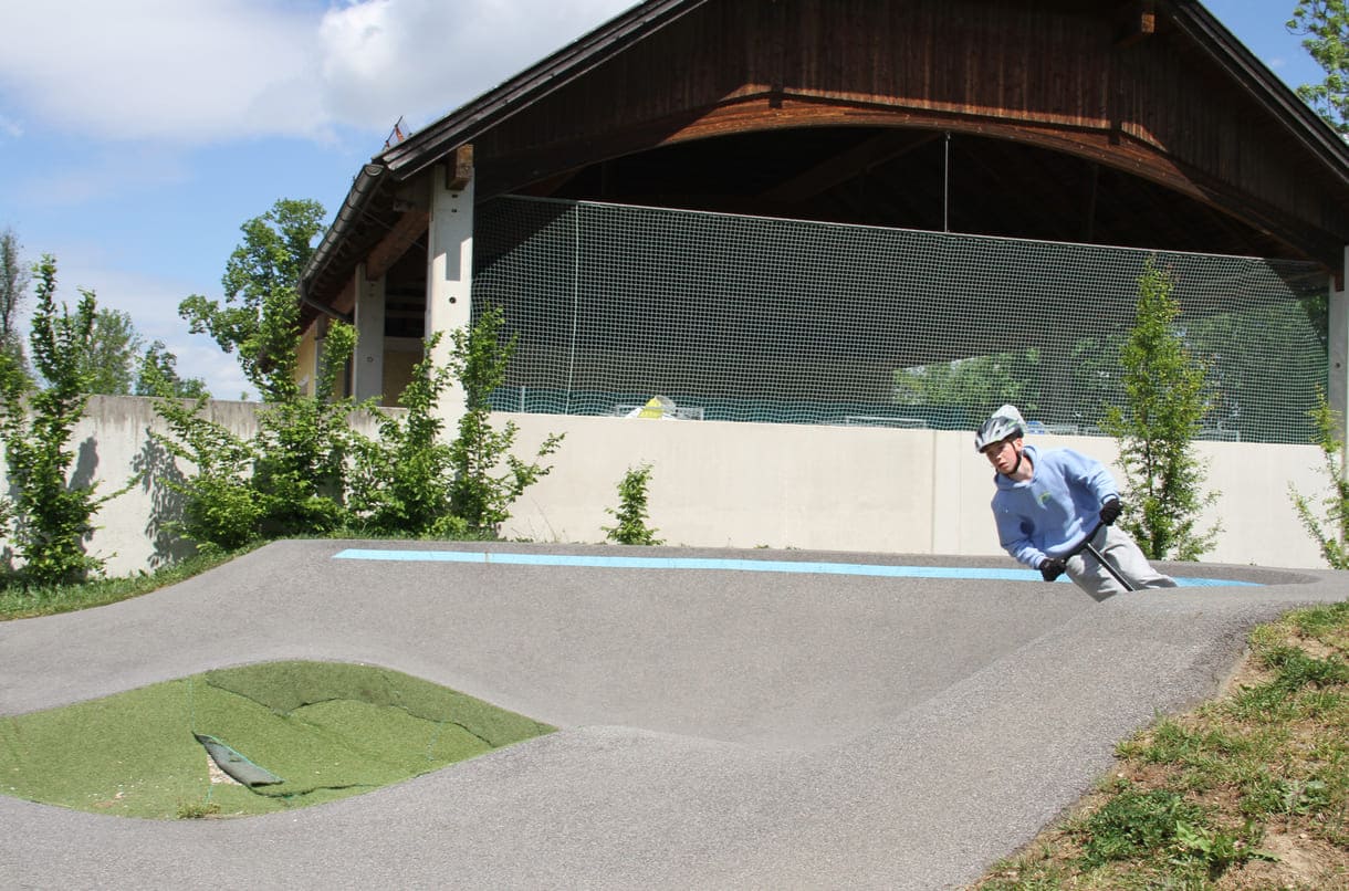 Einer des Radler-Trios düst auch mit einem Scooter über die Pumptrack-Strecke