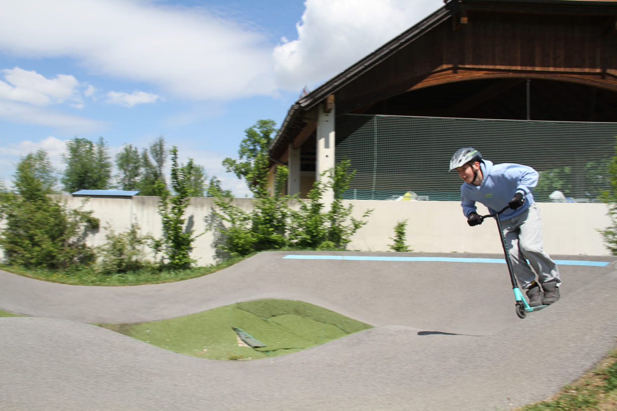 Einer des Radler-Trios düst auch mit einem Scooter über die Pumptrack-Strecke