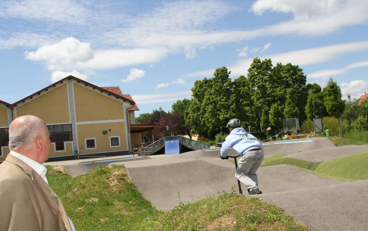 Einer des Radler-Trios düst auch mit einem Scooter über die Pumptrack-Strecke