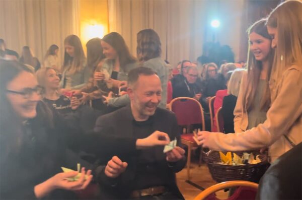 Schüler:innen verteilen Papierkraniche an die Festgäst:innen