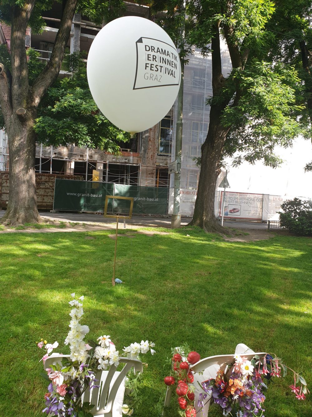 Plastikstühle mit Plastikblumen, ein leerer Bilderrahmen und ein großer weißer Ballon