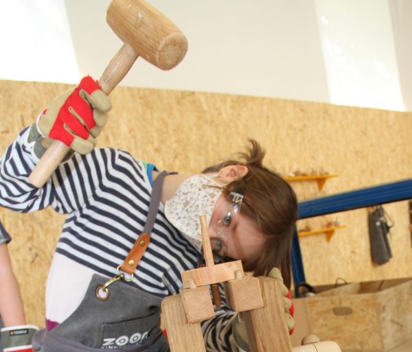 Kind schlägt Holzspitz durch Loch der Holzscheibe