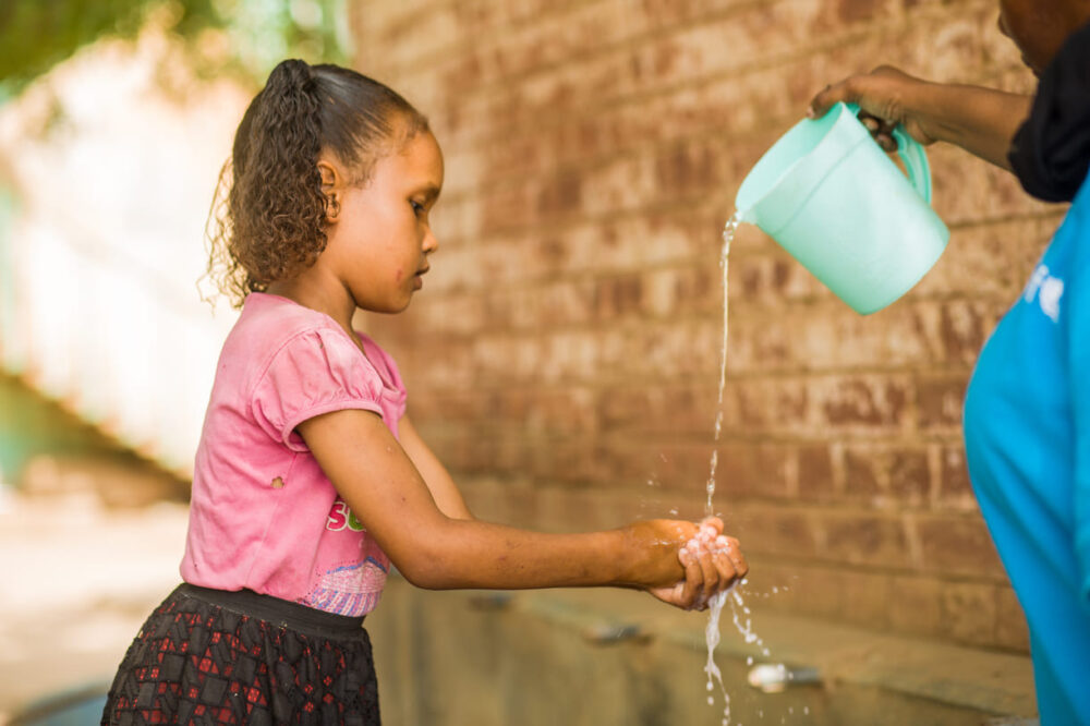 Die 10-jährige Rahaf wäscht sich an einem Sammelpunkt in Madani die Hände. An dem Treffpunkt, an dem 36 Familien und 86 Kinder leben, verteilte UNICEF Hygienesets für Frauen und sensibilisierte sie für angemessene Hygiene- und Hygienepraktiken, einschließlich Händewaschen mit Seife.