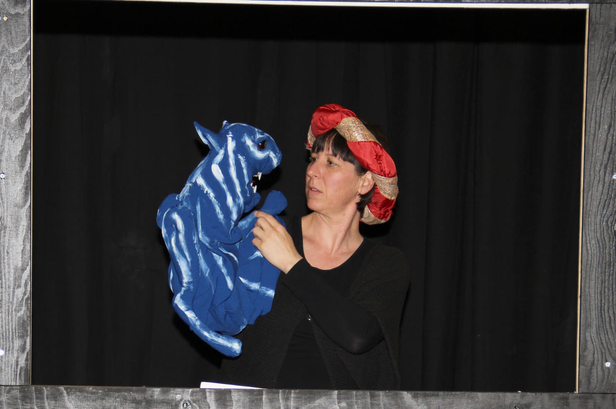 Die Puppenspielerin als Färber Hakim mit blauem Tiger als Handpuppe